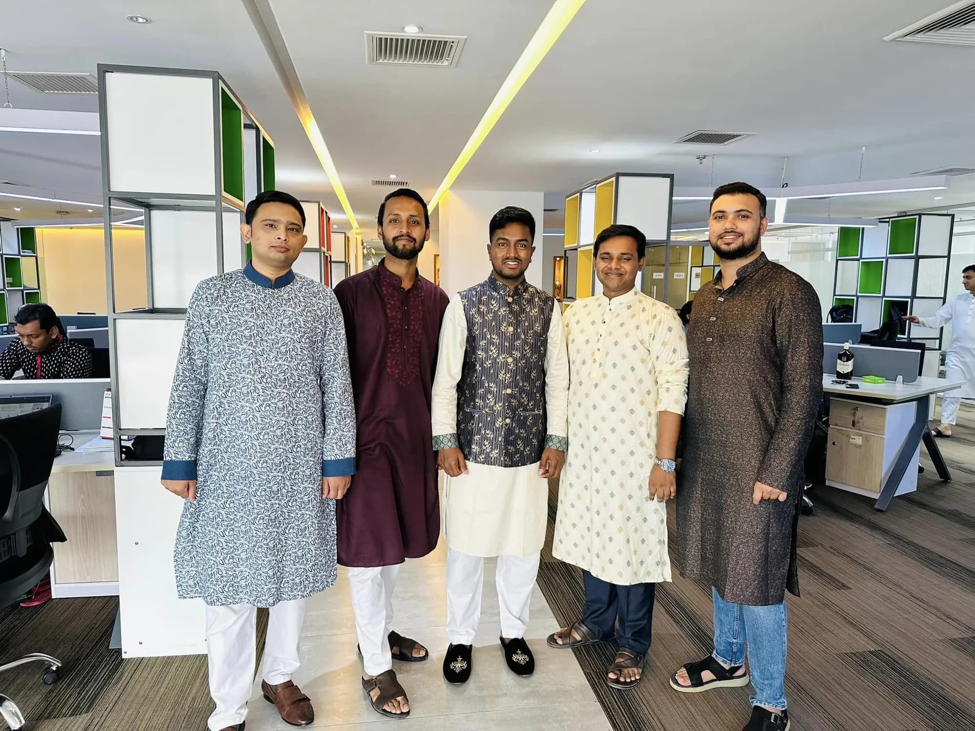 Five colleagues in traditional panjabi posing in an open-plan office