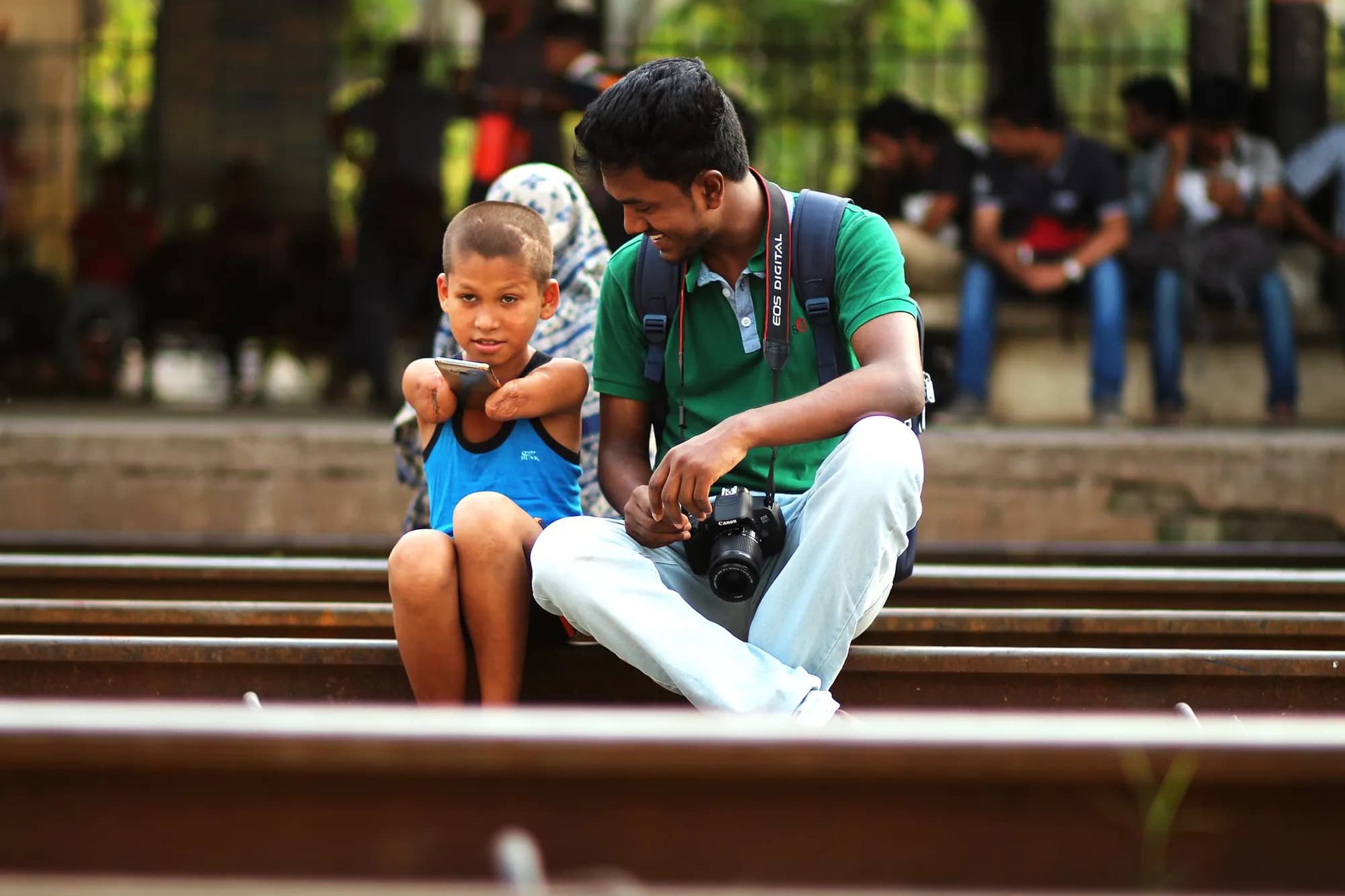 Sitting with a camera beside a child on a railway platform